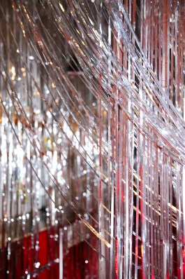 Rauminstallation von Elena Antoni für die Lecture Perfomance Spielen um Geld mit glänzenden, silbernen Lametta-Streifen vor rotem Hintergrund. elena antoni, innenarchitektur, szenografie, kreative beratung, basel, schweiz, deutschland